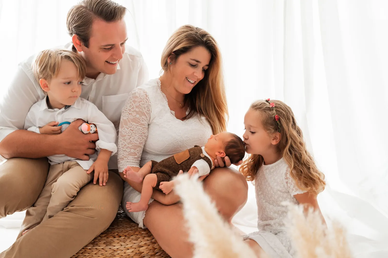 Eltern mit drei Kindern beim Familienfotoshooting im hellen Studio