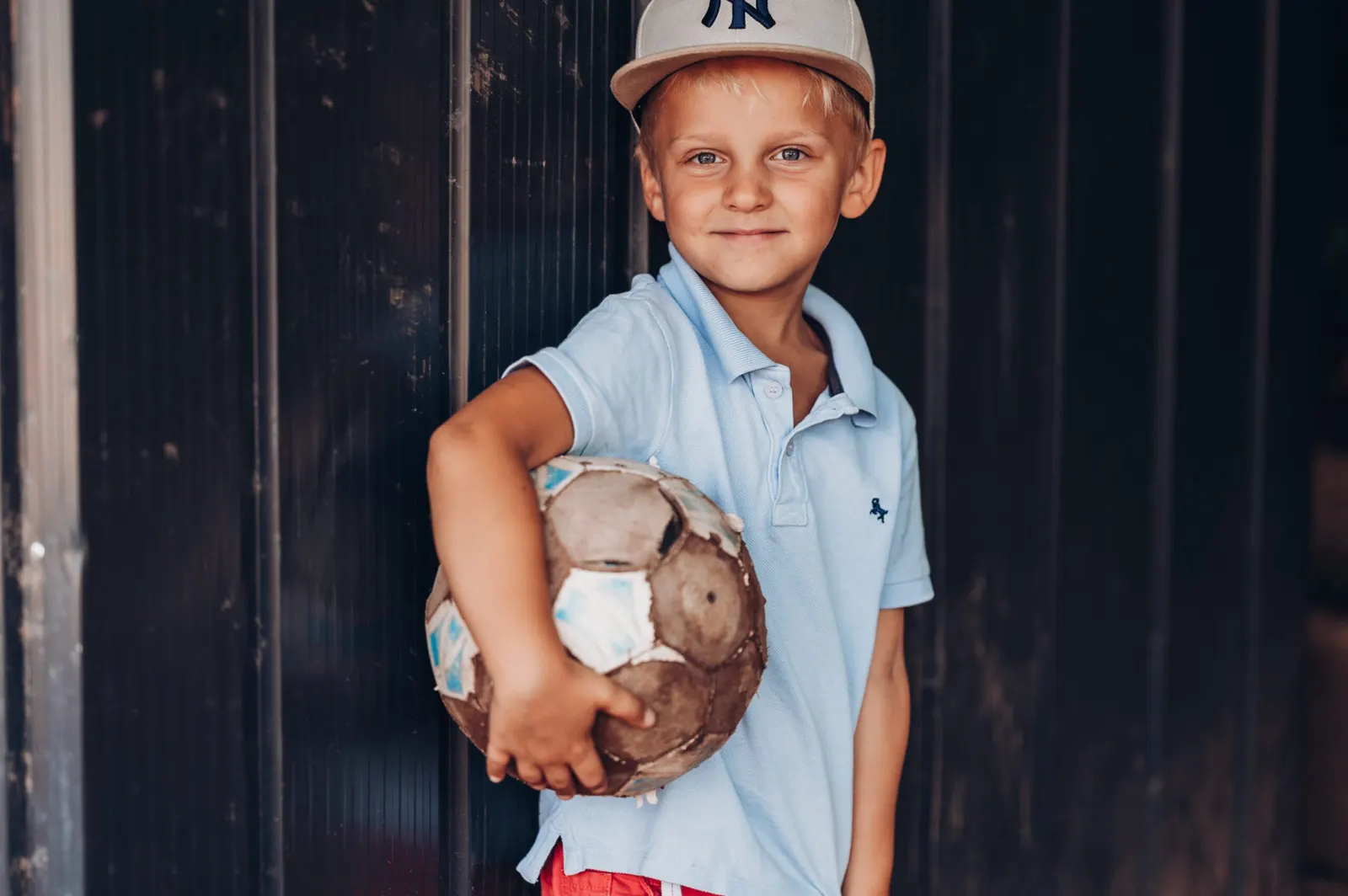 Grundschulkind mit Stoffhase vor einer Holzwand