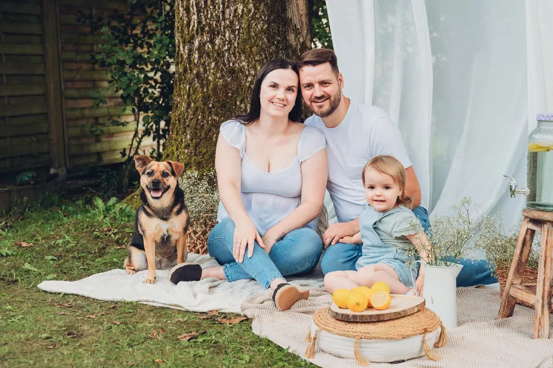 Familie mit Hund beim Mini-Shooting auf einer Decke im Grünen